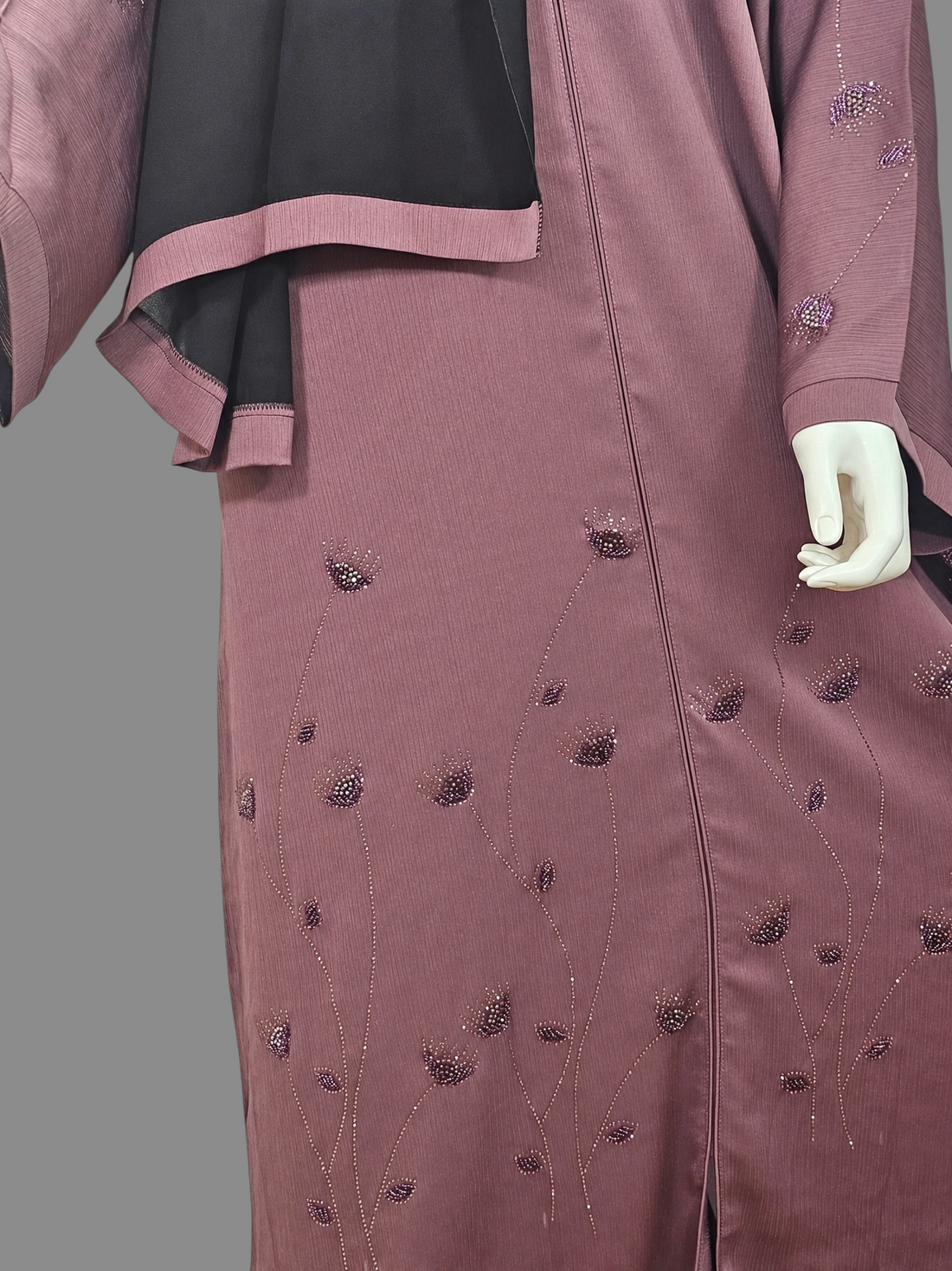 Close-up of beaded floral detail and front zip on dusty mauve abaya with black hijab