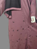 Close-up of beaded floral detail and front zip on dusty mauve abaya with black hijab