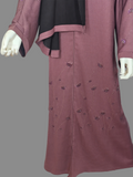 Dusty mauve beaded floral abaya with black hijab draped and front zip, on a mannequin