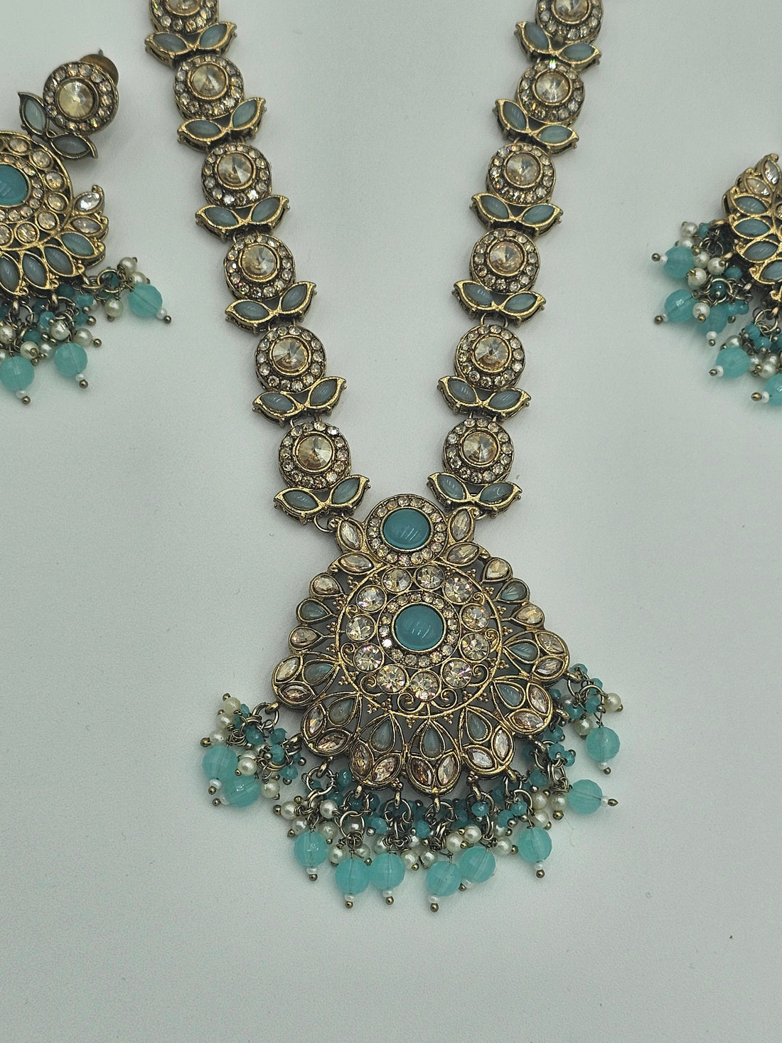 BelleNoor aqua blue kundan necklace set with antique gold finish, floral pendant, and matching jhumka earrings.