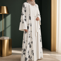 BelleNoor white abaya featuring a black and grey floral branch print, wide sleeves, and a matching waist tie and hijab.