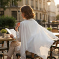 BelleNoor white polyester Nida khimar with tie back worn by a woman reading at an outdoor cafe table.