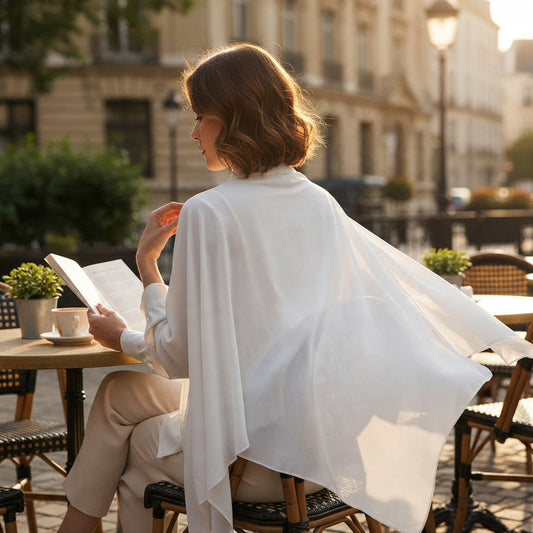 BelleNoor white polyester Nida khimar with tie back worn by a woman reading at an outdoor cafe table.